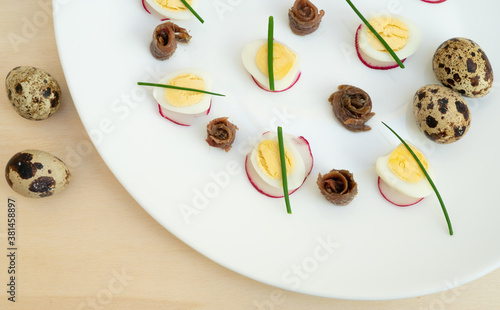 boiled quail eggs with anchovies and chives on a plate