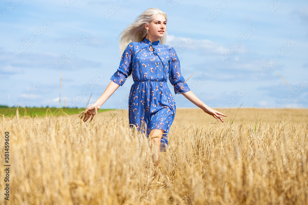 young happy blonde in a blue dress posing in a wheat field young happy blonde in a blue dress posing in a wheat field