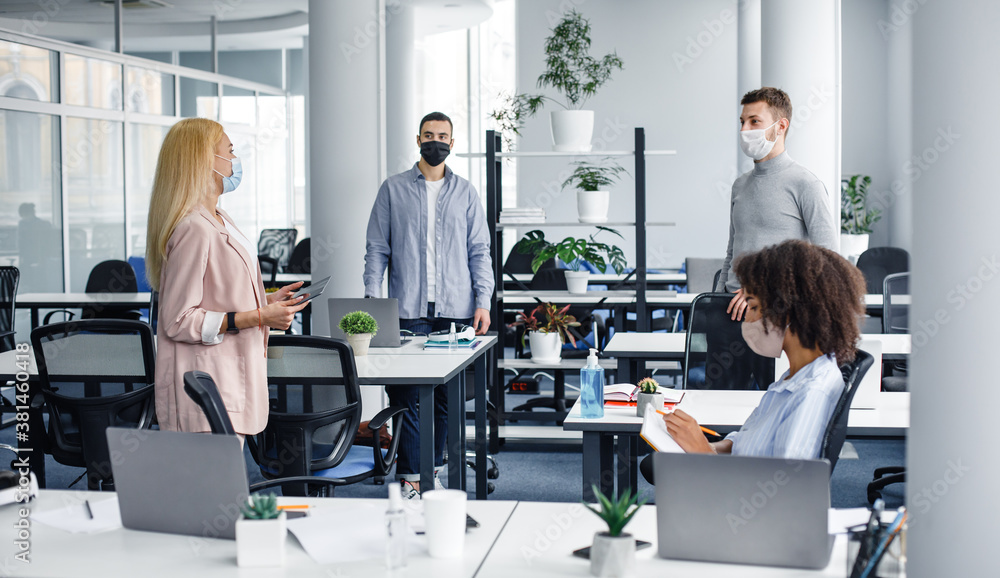 Meeting and new tasks from manager during covid-19 epidemic. Woman in business suit and protective mask speaks with workers, african american lady takes notes Meeting and new tasks from manager during covid-19 epidemic. Woman in business suit and protective mask speaks with workers, african american lady takes notes