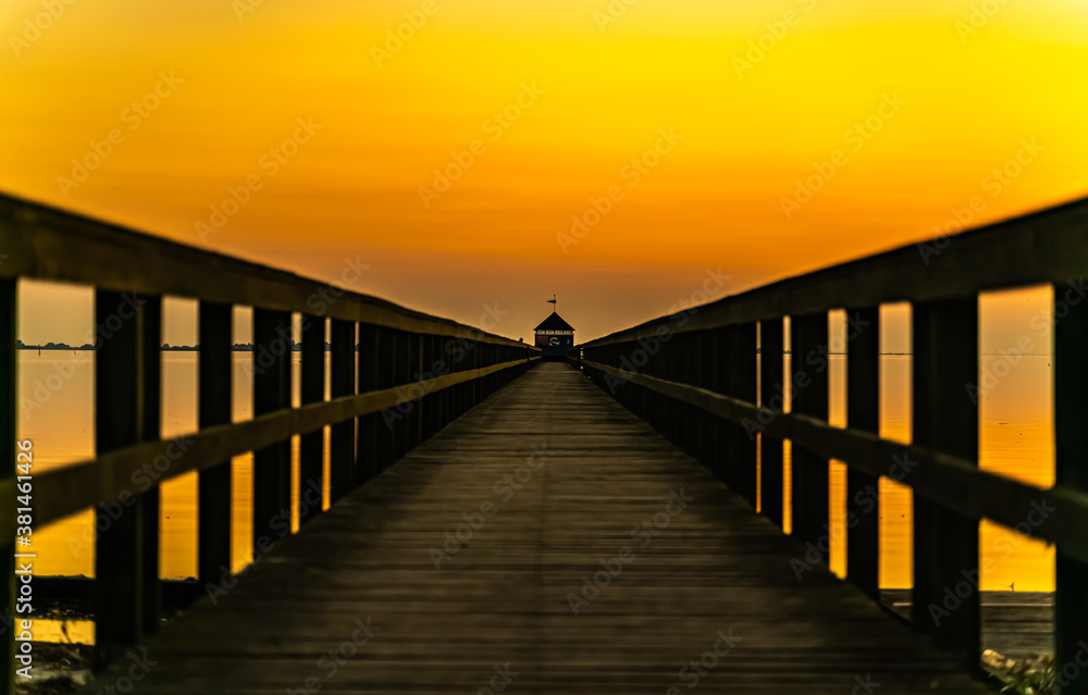 Wooden pier by the ocean at sunset, view down along the boardwalk.