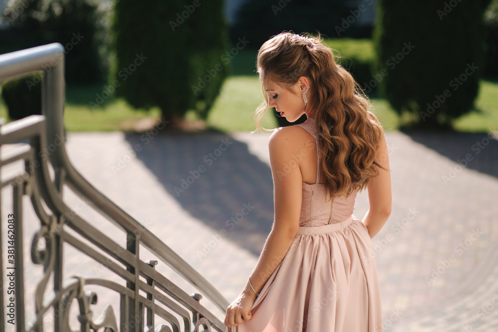 Attractive young woman in gorgeous evening dreess and curly hair posing to photographer Attractive young woman in gorgeous evening dreess and curly hair posing to photographer