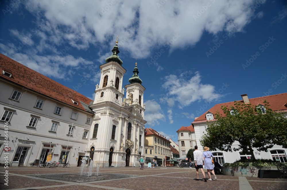 Graz, Austria - August 19, 2020: Mariahilfer church and square with crowded people walking by, in sunny day, famous tourist attraction in Graz, Styria region, Austria