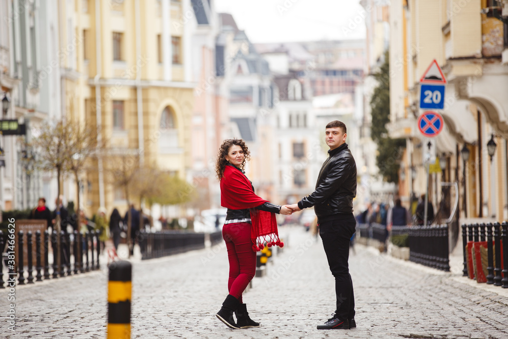 rock style couple in the old City. Happy lovers on the walk outdoor. Funny couple pair weared in black leather jackets. Romantic walk of young happy family. Red and black clothes