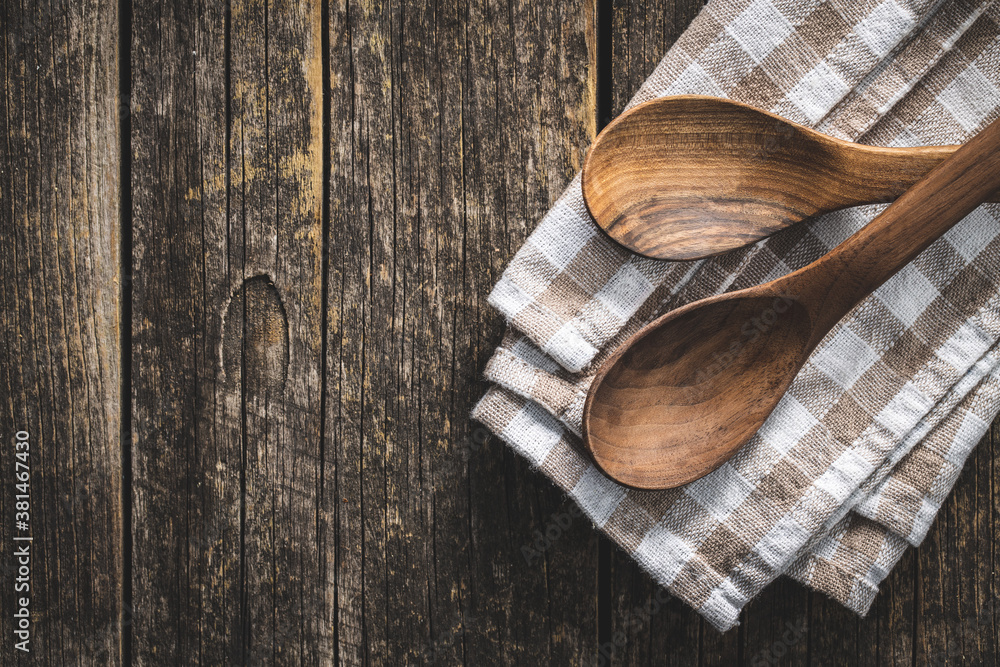 Two wooden spoons on checkered napkin on old wooden table. Two wooden spoons on checkered napkin on old wooden table.