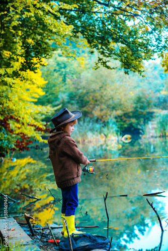 Child learning how to fish, holding a rod on a lake. Kid with fishing rod. American children. © Volodymyr