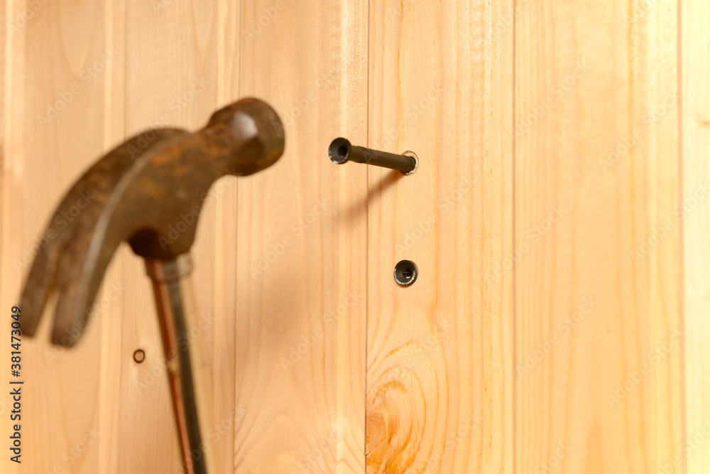 the hammer hits the dowel and hammers it into a hole in the wooden wall the hammer hits the dowel and hammers it into a hole in the wooden wall