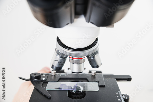 Using a biological microscope. Close-up of the microscope lens. Scientific research concept, using a microscope. Medical examinations, searching for bacteria, diseases, blood tests.