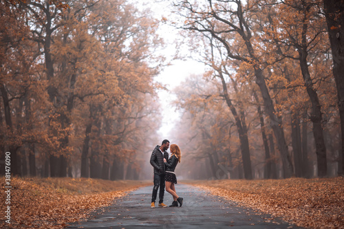Interracial couple posing in autumn park road