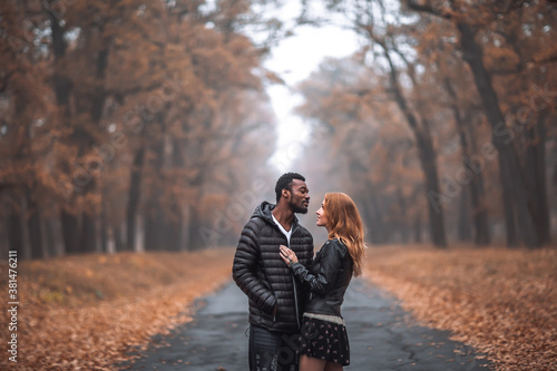 Interracial couple posing in autumn park road