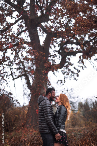 Interracial couple posing in autumn leaves background © onphotoua