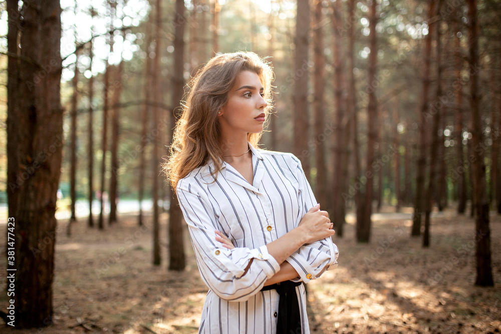 Beautiful young woman standing in the park with cross hands and looking at the side, in the sunny day. Beautiful young woman standing in the park with cross hands and looking at the side, in the sunny day.