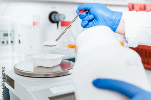 Photos Pharmacist pouring white powdered chemical