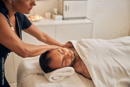 Professional masseur massaging young man body at spa salon