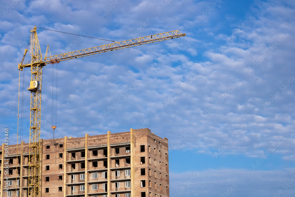 Yellow tower crane at a construction site. House under construction. Yellow tower crane at a construction site. House under construction.