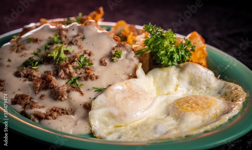 Closeup image of a hearty breakfast of eggs and chicken fried steak with cheesy potatoes.