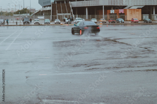 Cars are drifting in the old parking lot. Rain drift. Gray photo processing, atmosphere. Racing in the city.