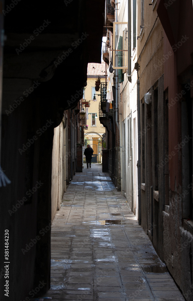 Venice unusual view of city, details and unusual Venice's spots, halley with traditional italian lamps, suggestive view of a traditional Venetian Calle with a man walking in dinstance
