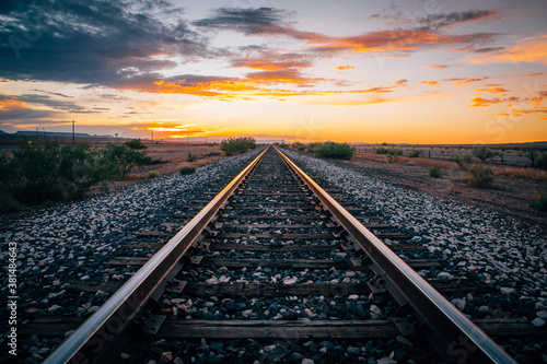Empty train tracks going into the horizon at sunset in the desert