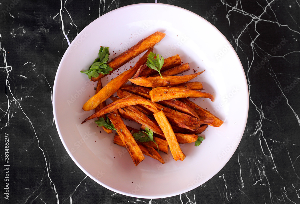 Home made freshness roasted sweet potatoes wedges on marble background Home made freshness roasted sweet potatoes wedges on marble background
