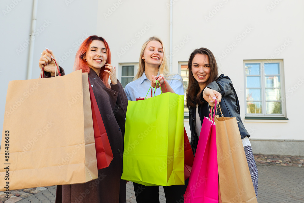 Three young female friends with colorful bags after shopping Three young female friends with colorful bags after shopping