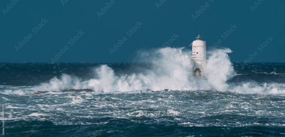 The lighthouse of the Mangiabarche shrouded by the waves of a mistral wind storm
