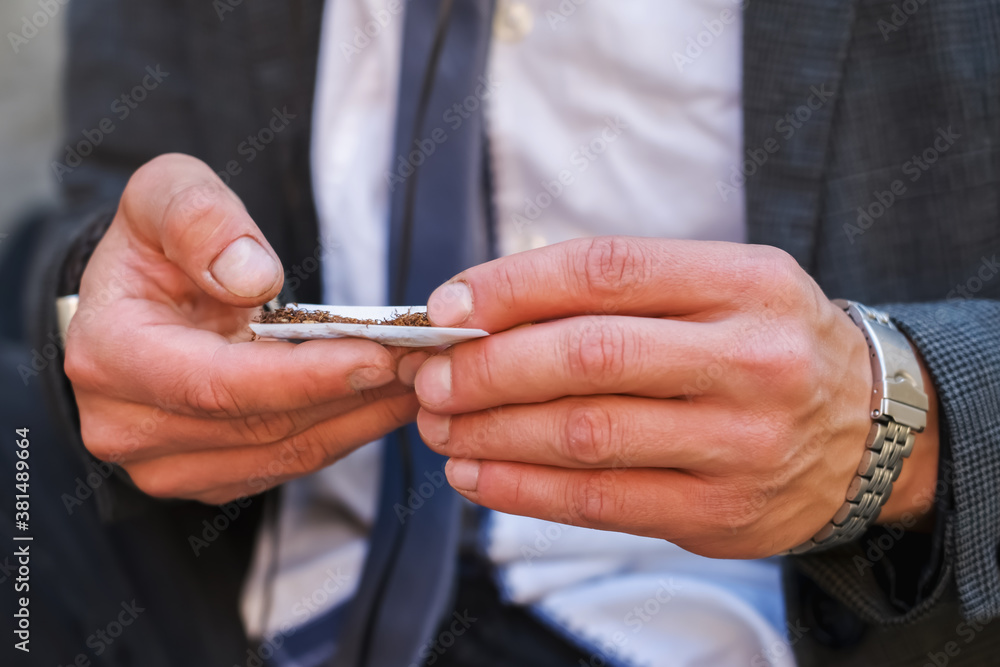 Portrait of the man rolling a cigarette. Addiction and health concept. Portrait of the man rolling a cigarette. Addiction and health concept.