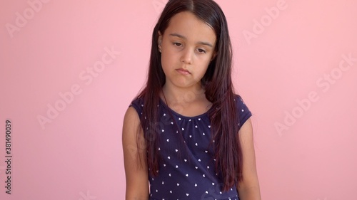 Portrait of a sad little girl pink background