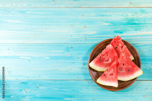 Four slices of ripe watermelon on a plate. Blue wooden table. The view from the top