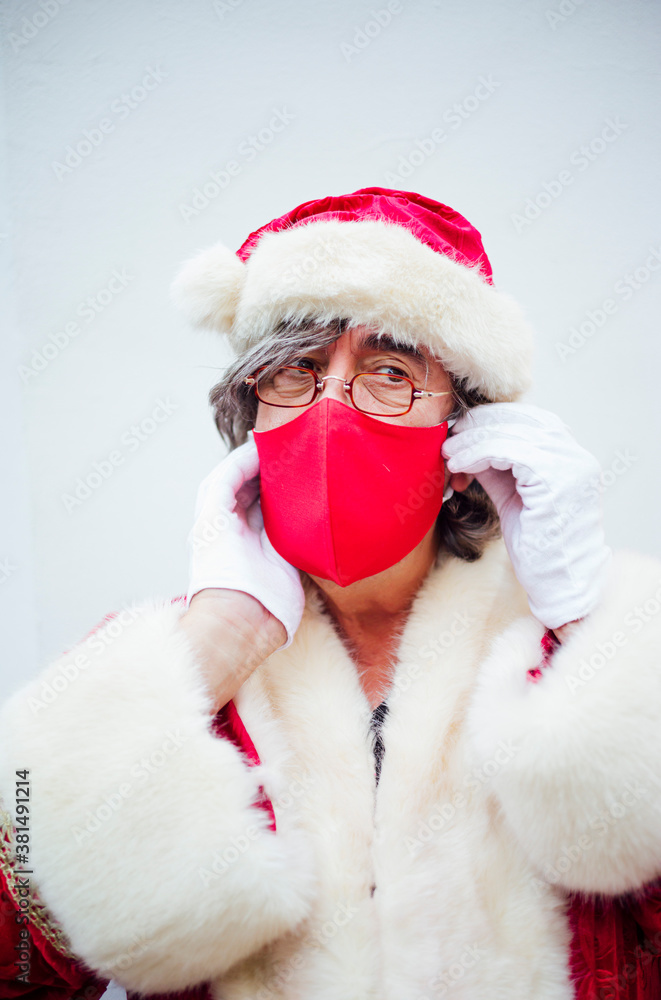 Santa Claus walking through the streets of the city of MadridSanta Claus putting on a mask in the city of Madrid. Santa Claus walking through the streets of the city of MadridSanta Claus putting on a mask in the city of Madrid.