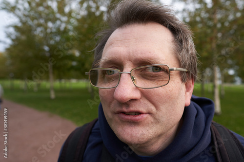happy man face in glasses close-up, against the background of the Park