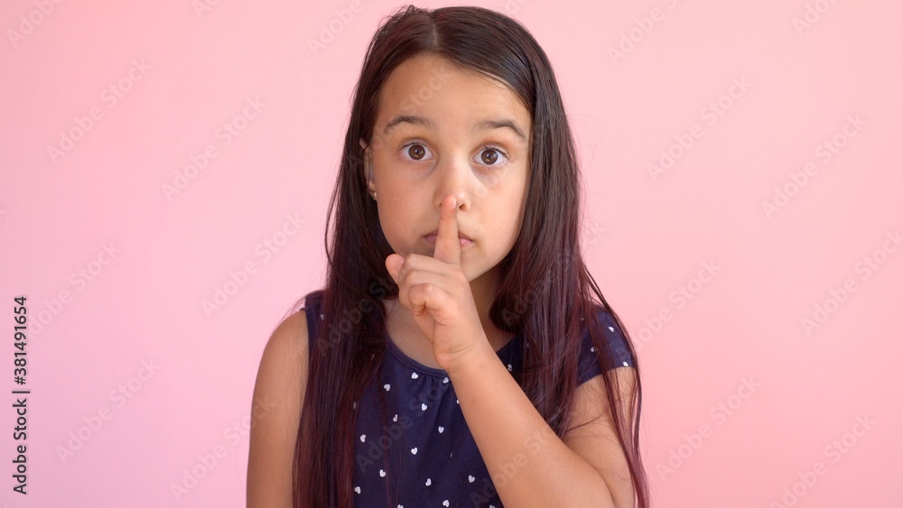 Girl show silent sign at pink background Girl show silent sign at pink background