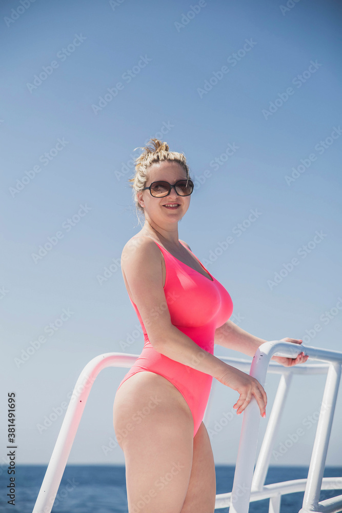 beautiful blonde with big breasts in a pink swimsuit sunbathing on