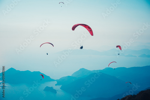 Fethiye, Mugla / Turkey August 28 2020: Paragliding in the sky. Paraglider tandem flying over the sea with mountains at sunset. Aerial view of paraglider and Blue Lagoon in Oludeniz, Mugla, Turkey.