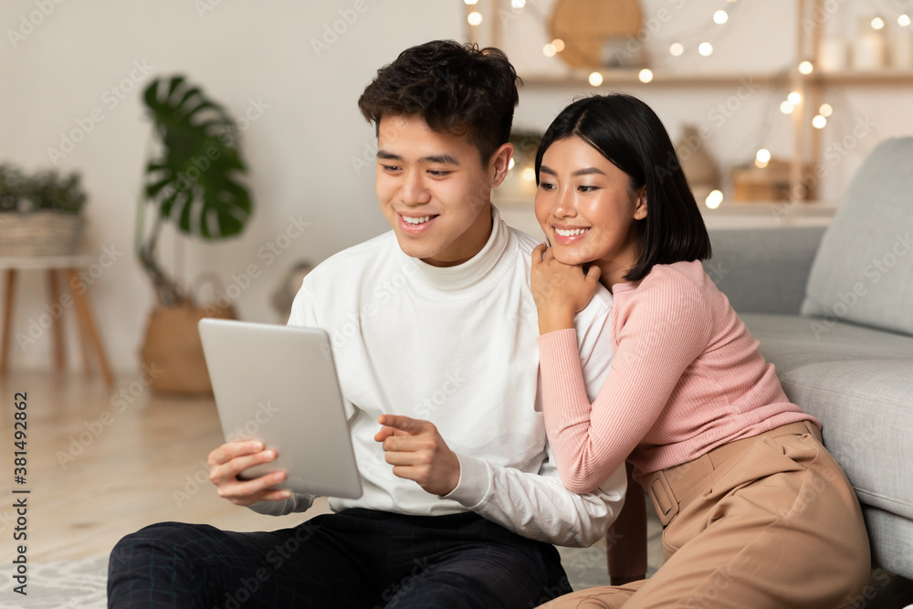 Happy Korean Couple Using Tablet Computer Sitting At Home Happy Korean Couple Using Tablet Computer Sitting At Home