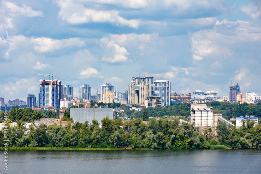 The beautiful cityscape of Kyiv with the Dnipro River, an industrial complex on the bank and new high-rise buildings on the horizon.