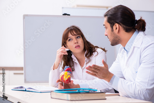 Young male doctor cardiologist and female student in the classro