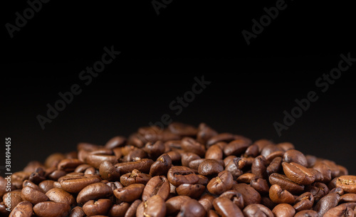 Coffee beans on a black background. Heap of coffee beans. Poured coffee close-up