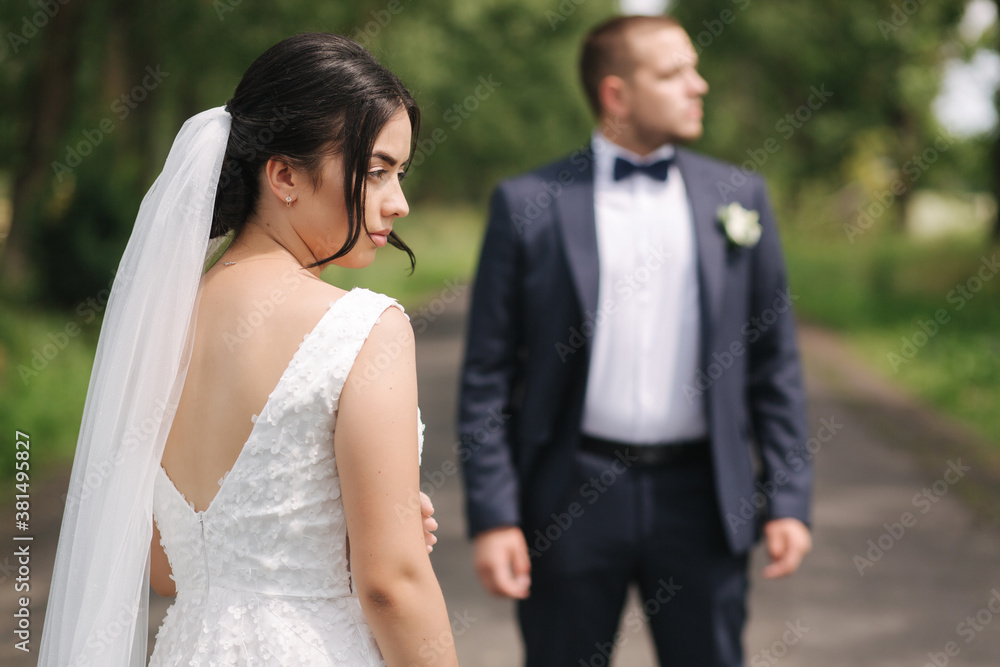 Newlyweds walking in the park on wedding day. Beautiful bride and handsome groom