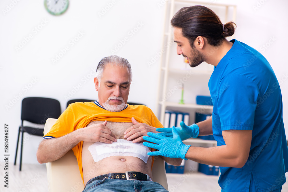 Old man visiting young male doctor Old man visiting young male doctor