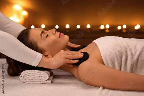 Young woman receiving hot stone massage at modern spa