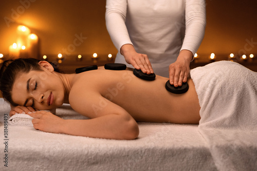 Joyful lady having hot stone massage at luxury spa