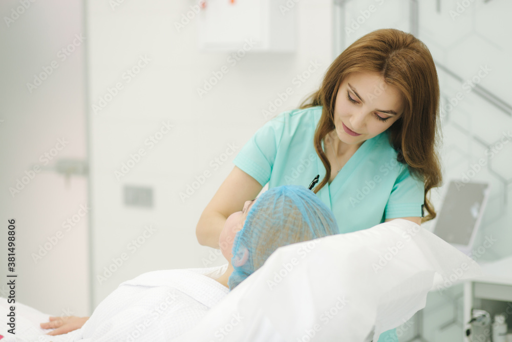 Obraz premium Hands of cosmetologist making preparation for face contouring plasty. Young woman gets beauty facial injections in salon. Aesthetic cosmetology