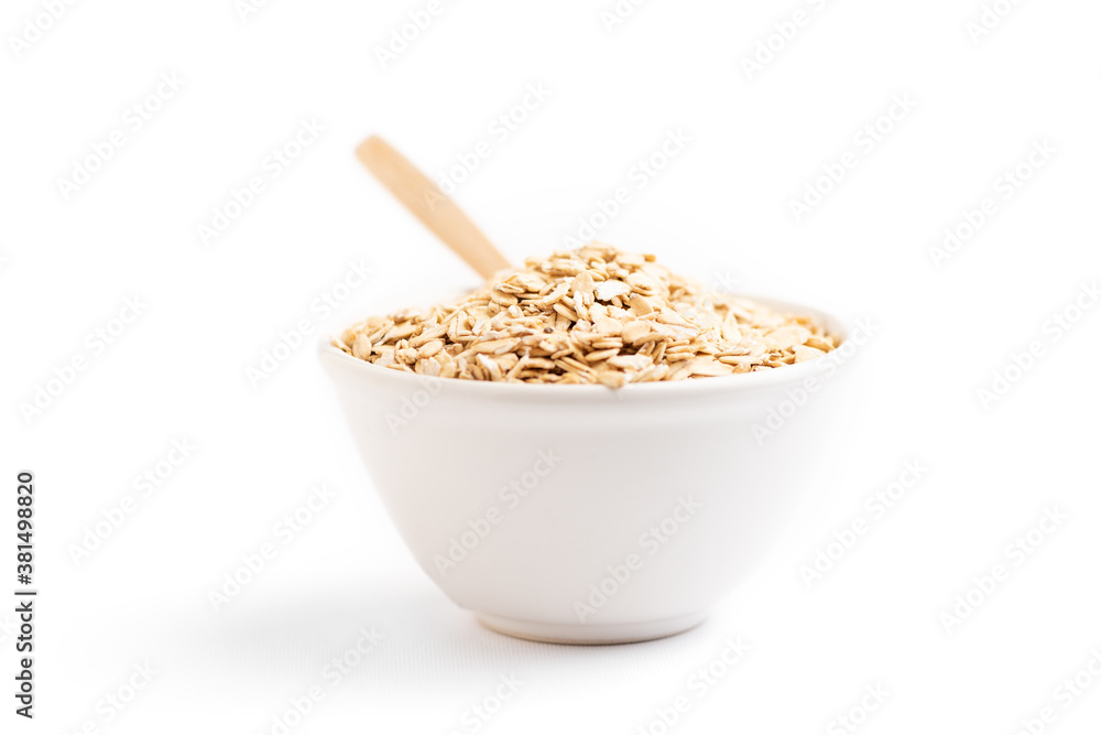 Oat flakes on a bowl and a wooden spoon Oat flakes on a bowl and a wooden spoon