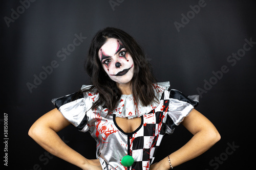 woman in a halloween clown costume over isolated black background skeptic and nervous, disapproving expression on face with arms in waist