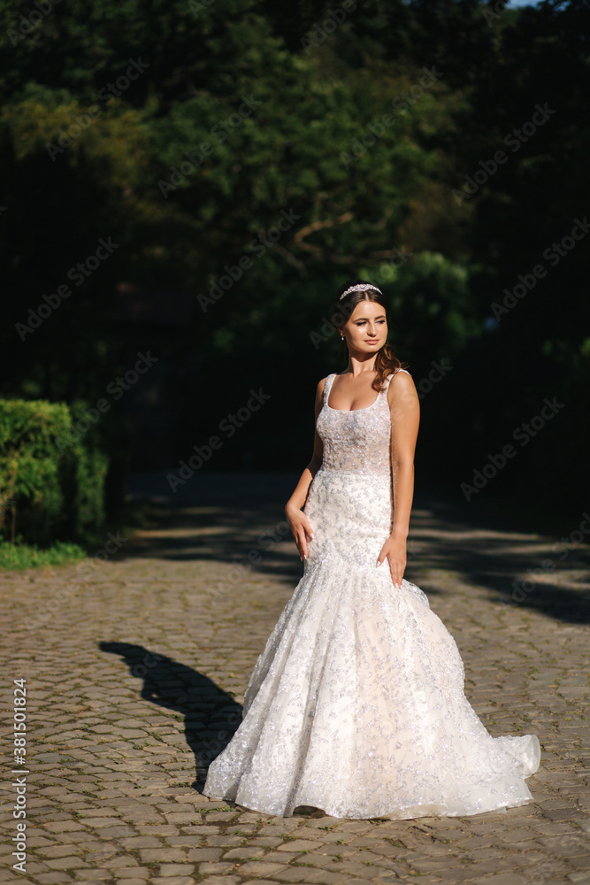 Attractive young bride model in beautiful wedding dress walking in the park