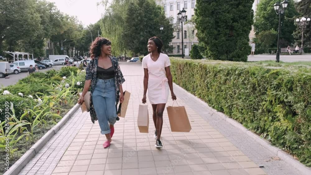 Two afro american women friends in the city. Friends on a shopping trip carrying colorful shopping bags. Two afro american women friends in the city. Friends on a shopping trip carrying colorful shopping bags.