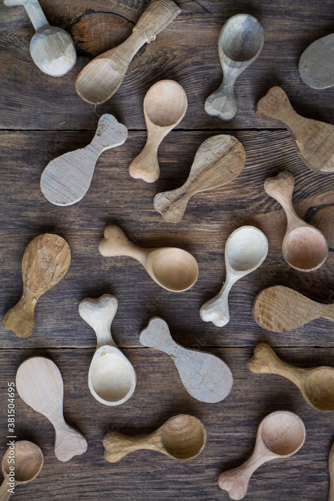 Handmade wooden utensils, top view lot of billets and spoons on wooden table, selective focus