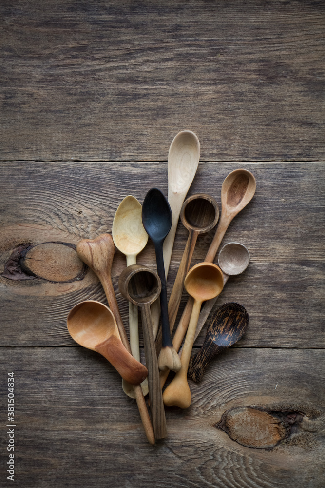 Top view lot of wooden spoons made of precious wood on wooden table, eco-friendly concept of cutlery, handmade tableware production Top view lot of wooden spoons made of precious wood on wooden table, eco-friendly concept of cutlery, handmade tableware production