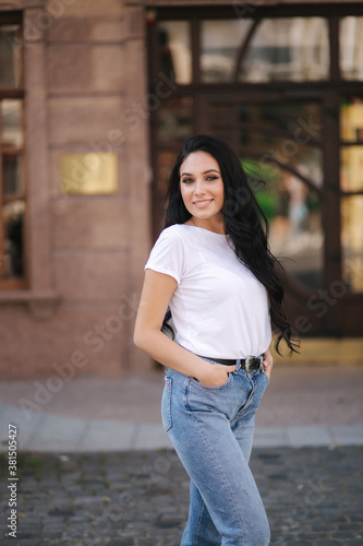 Attractive young woman in white shirt and jeans walking in the city