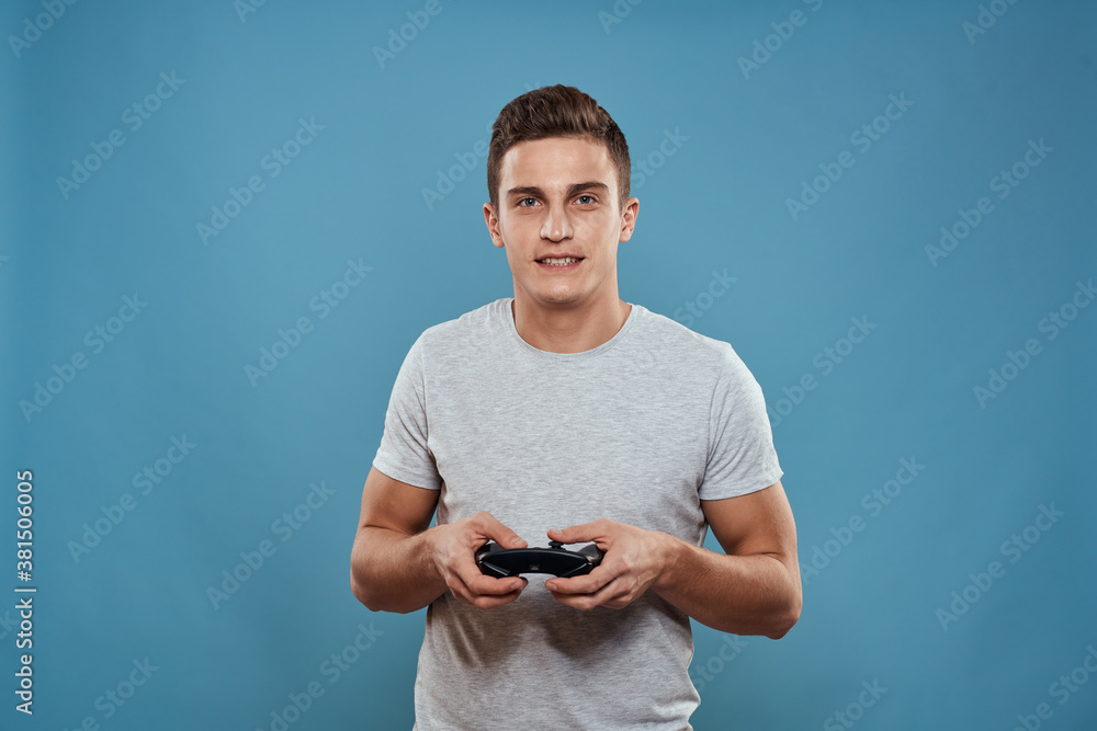 A man with a joystick in his hands entertainment leisure technology video games blue background white t-shirt A man with a joystick in his hands entertainment leisure technology video games blue background white t-shirt